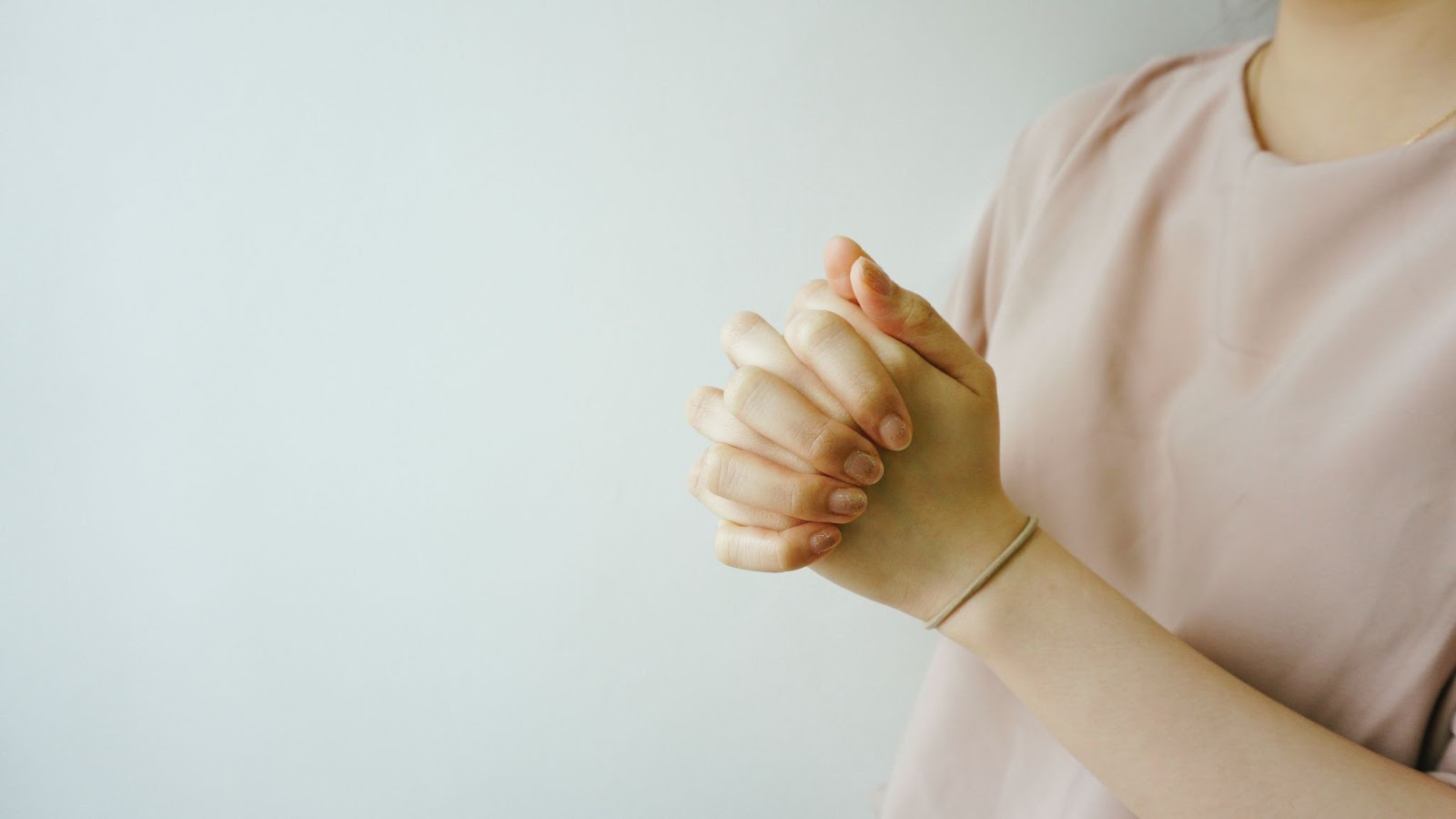 two hands of a person clasped in prayer
