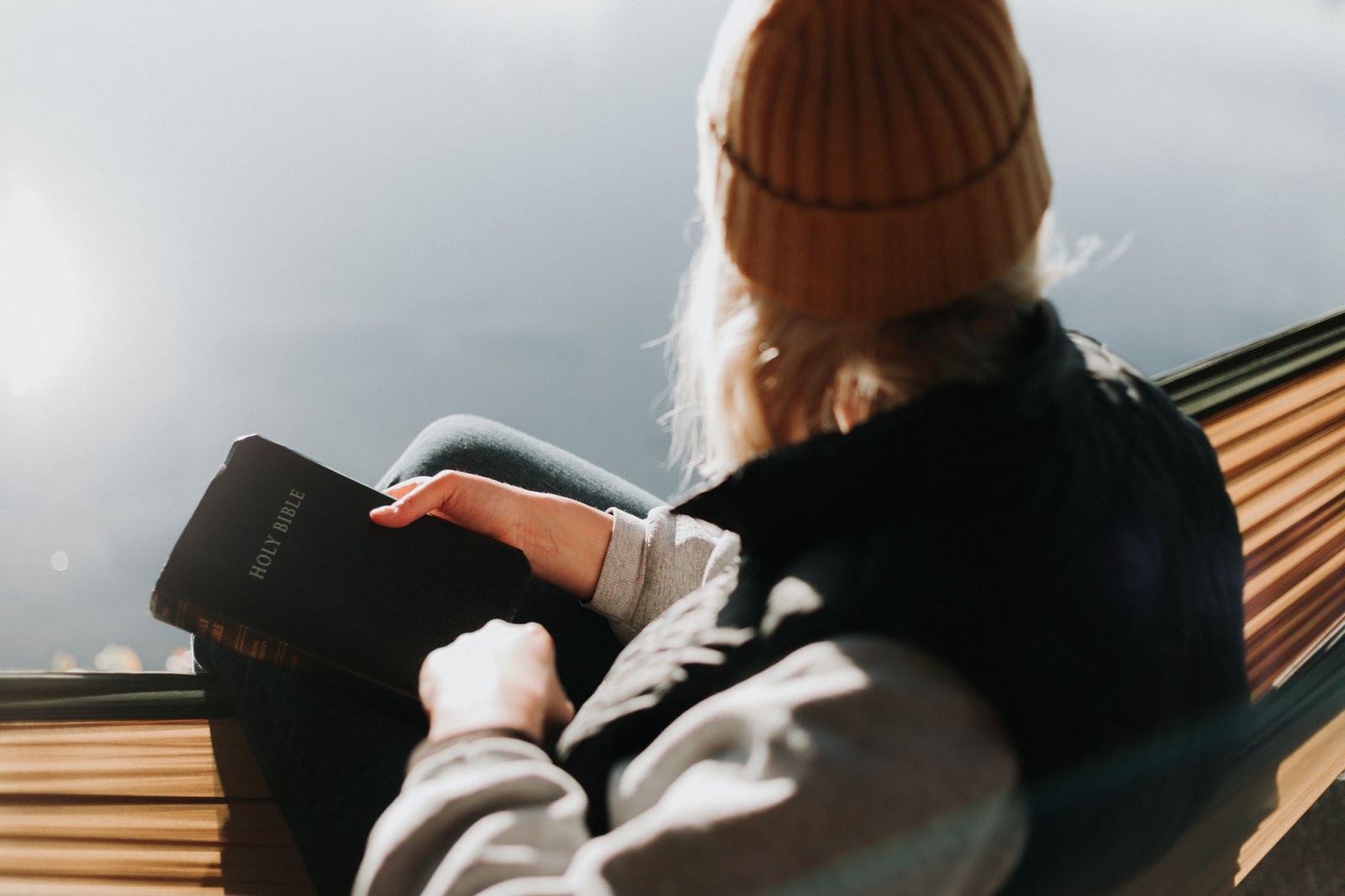 Women from behind sitting in hammock with a Bible in her hand.