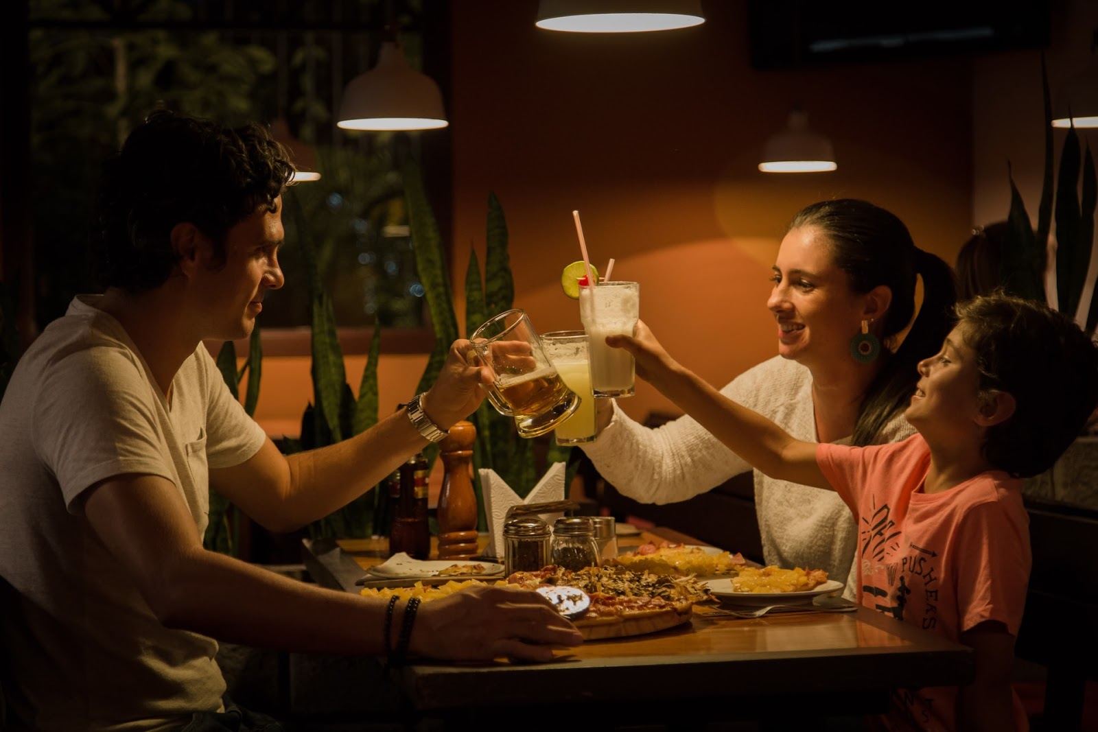  a family of three eating dinner and cheering their drinks