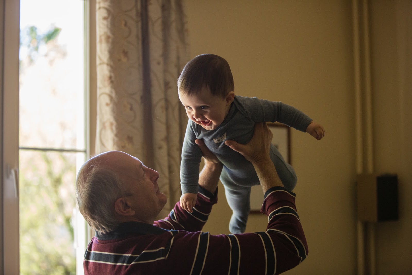 old man lifting a smiling baby into the air