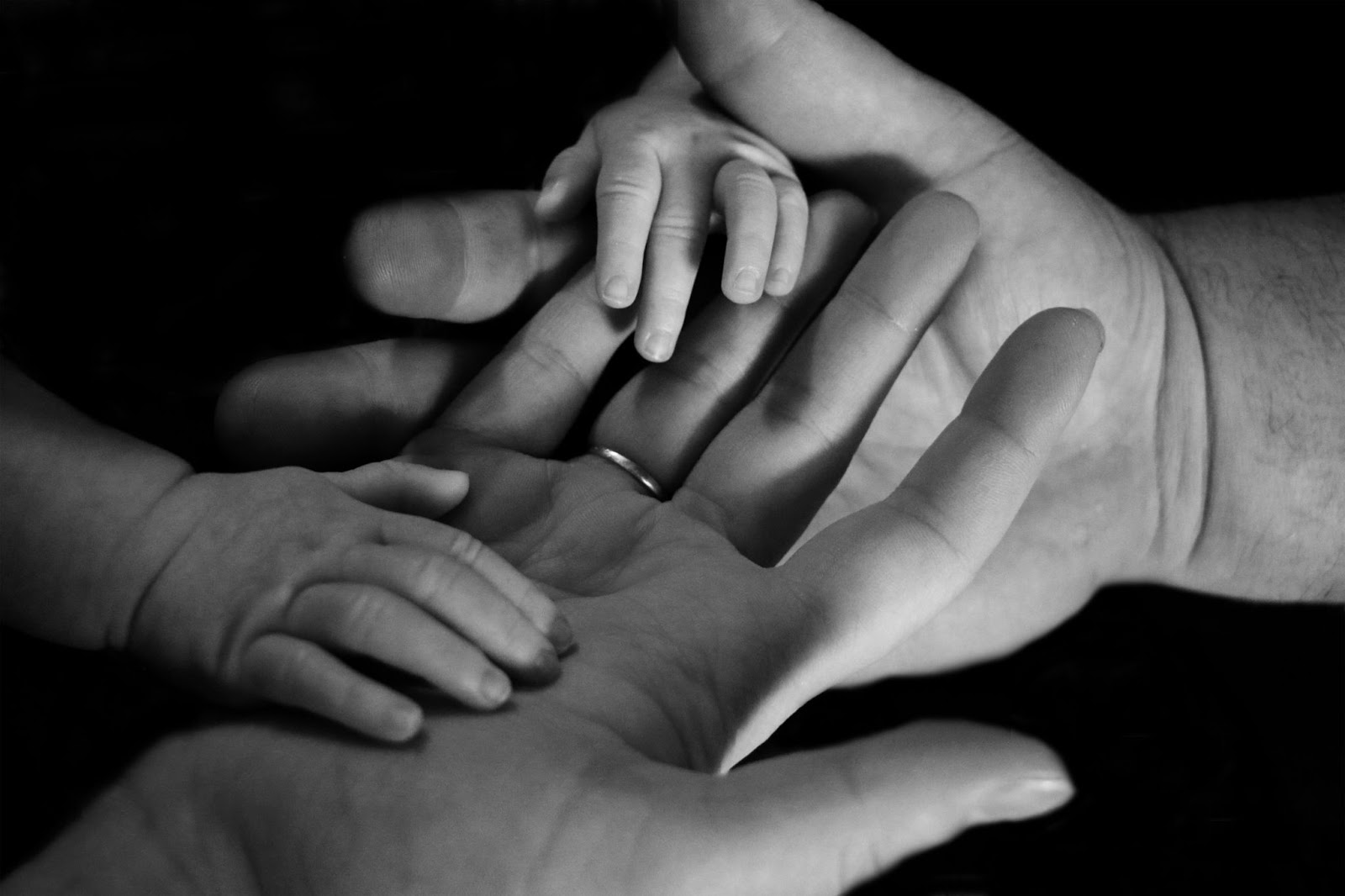 Two adult hands and two baby hands on top of each other