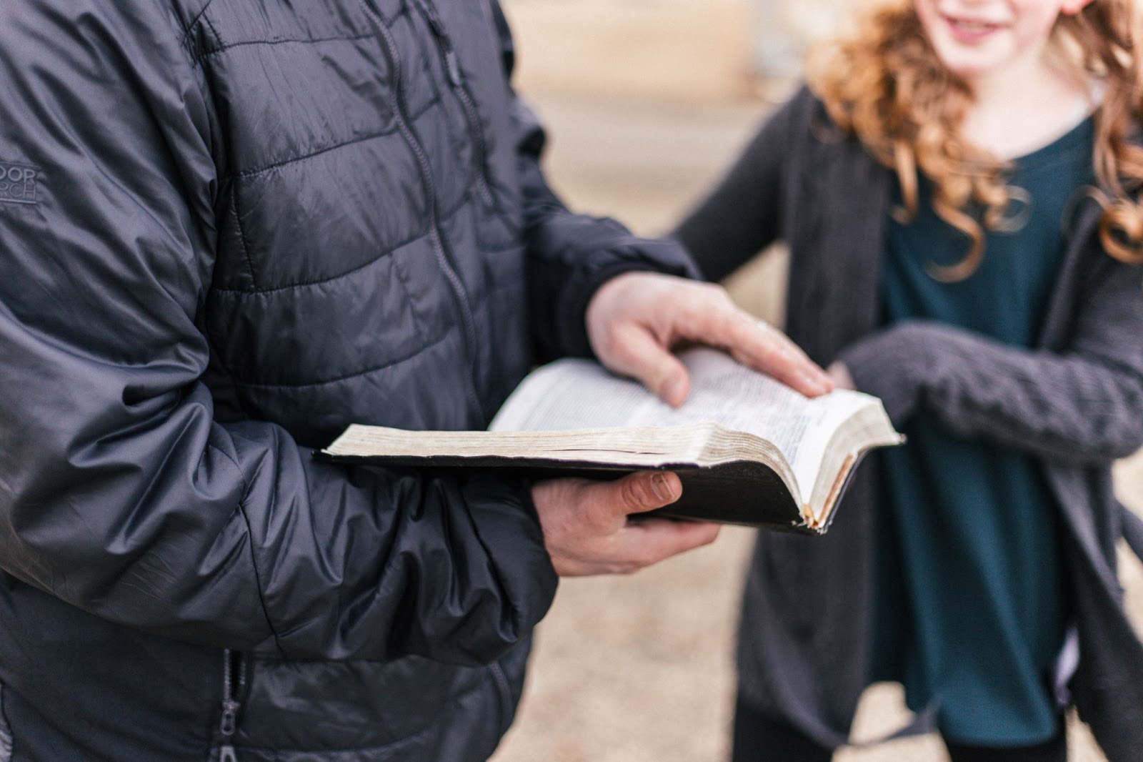 person holding scriptures with young girl next to him