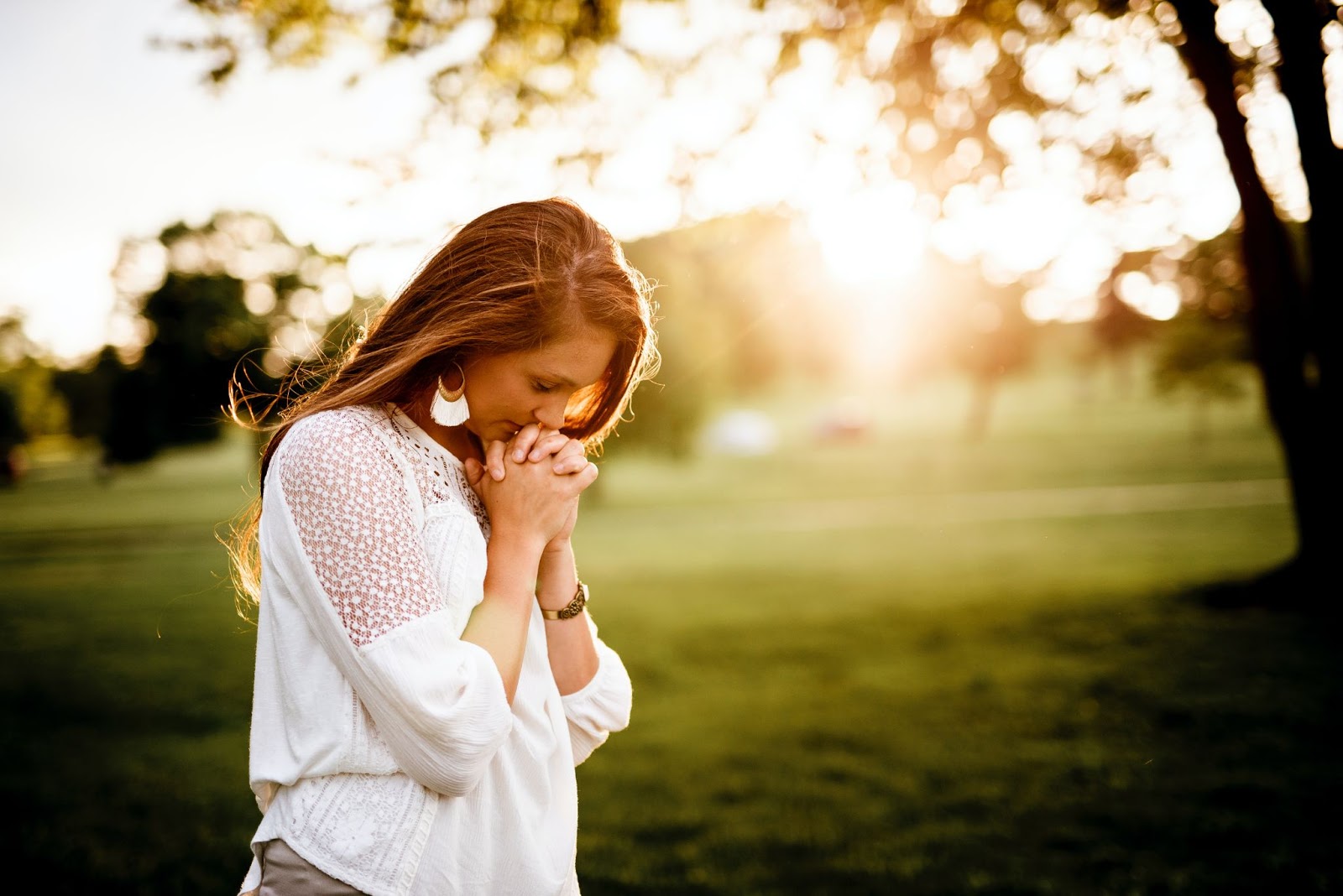 Woman praying outside with her head bowed