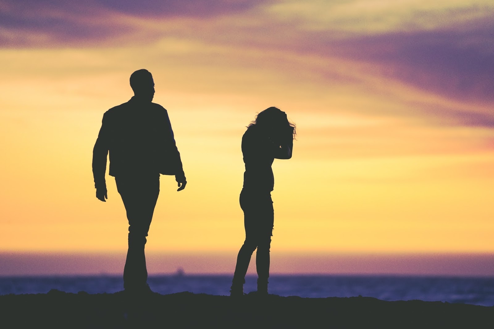 silhouette of a man walking away from a woman