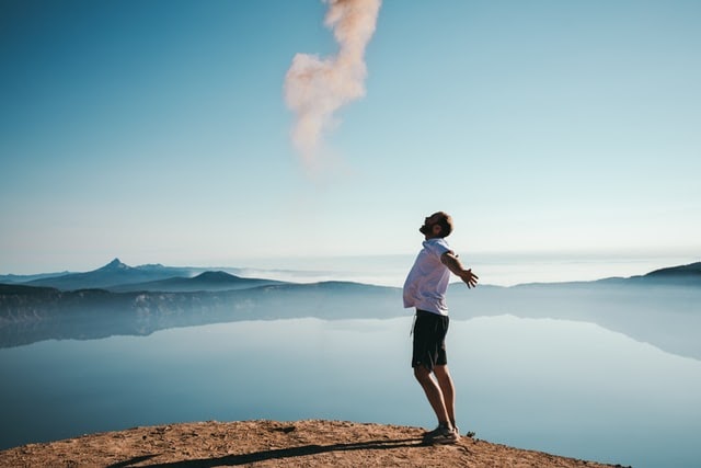 Happy man standing on shore, hands outstretched