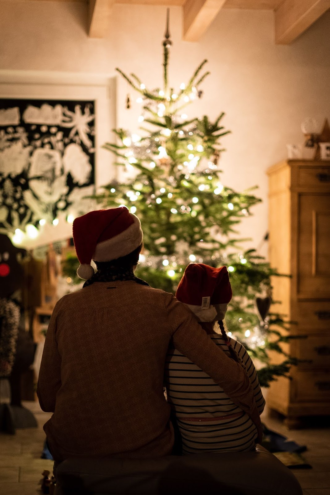 an adult and a child looking at a Christmas tree