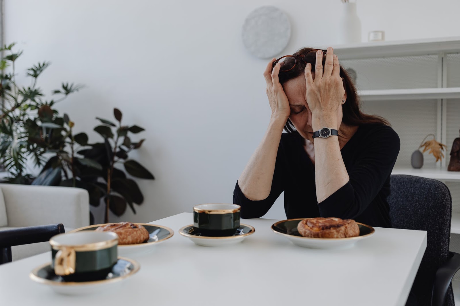 Woman sitting at a table with her fact in her hands.