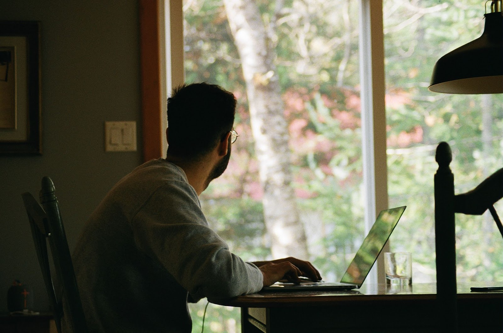 Man working at computer and looking out window.