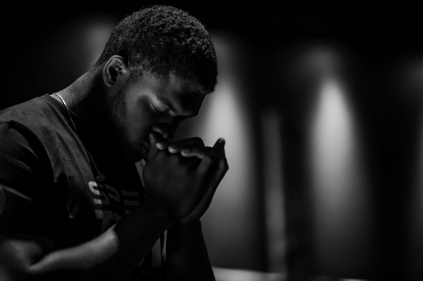 May praying with his eyes closed and hands near his mouth.