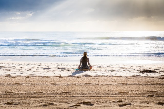 Woman meditating near ocean
