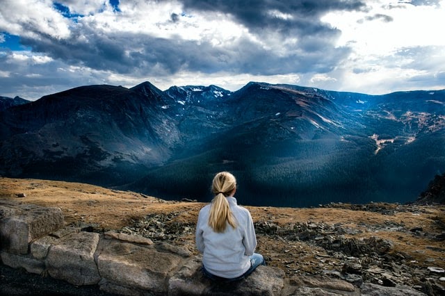 Woman sitting on a rock overlooking a high mountain view