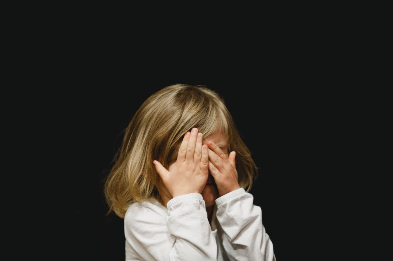 a child covering their face with their hands