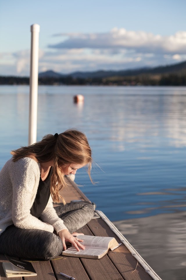 Woman reading Bible by the water's edge