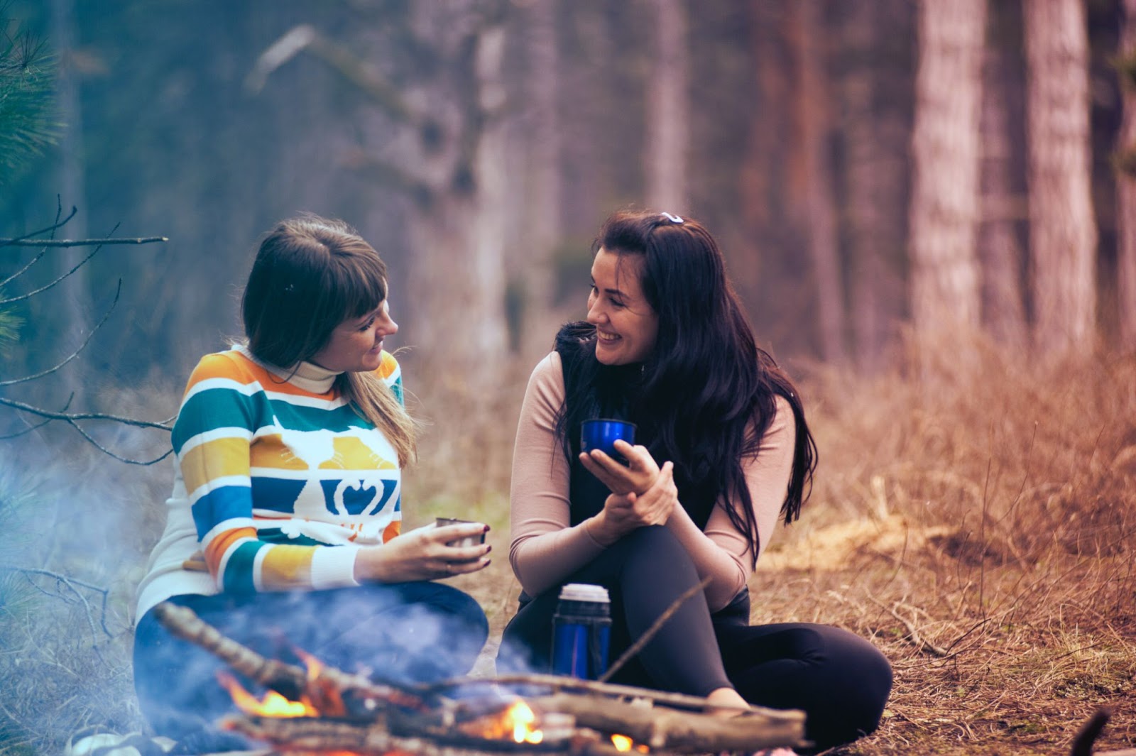 Women chatting and listening near a bonfire