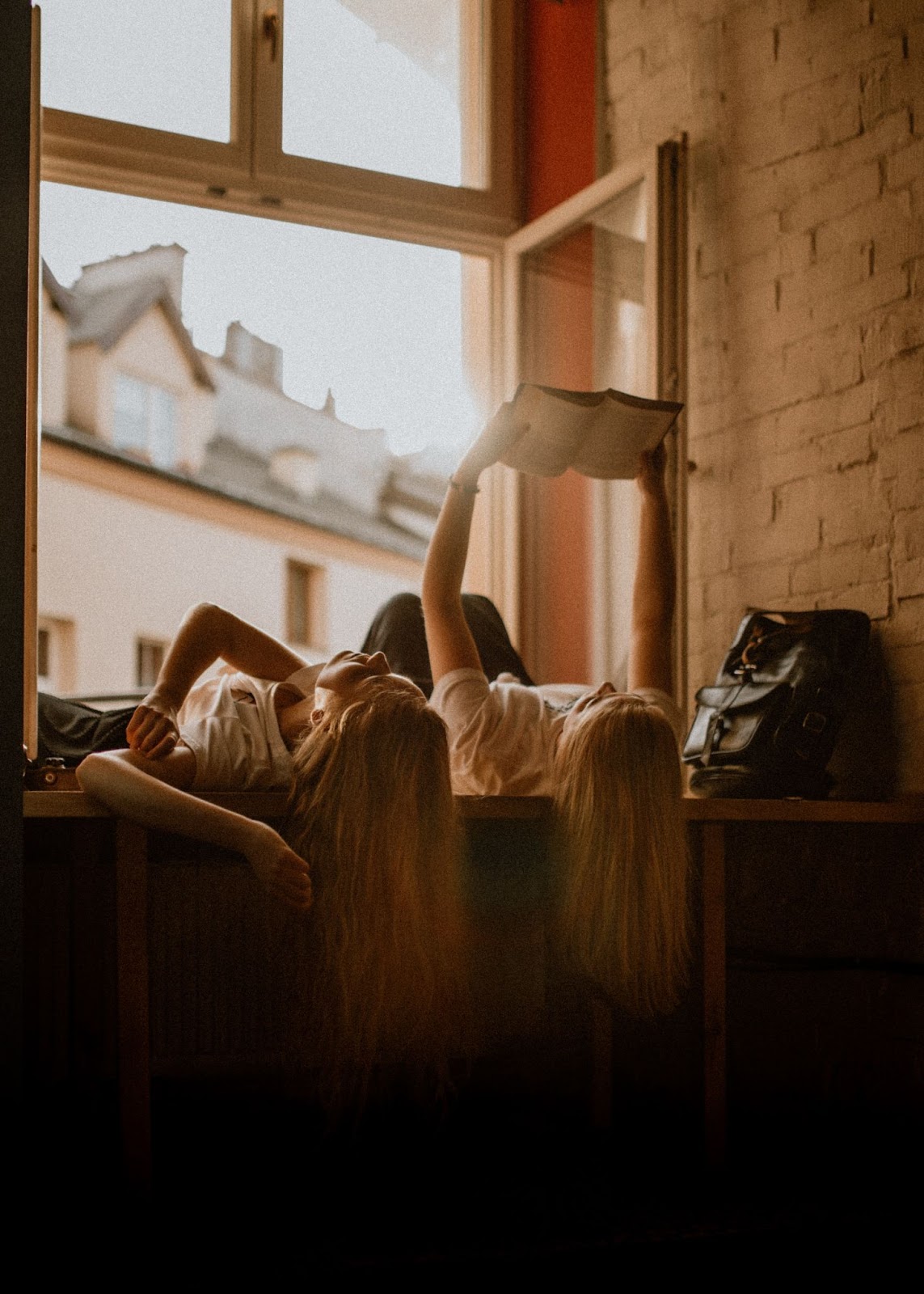 two girls lying down and reading a book