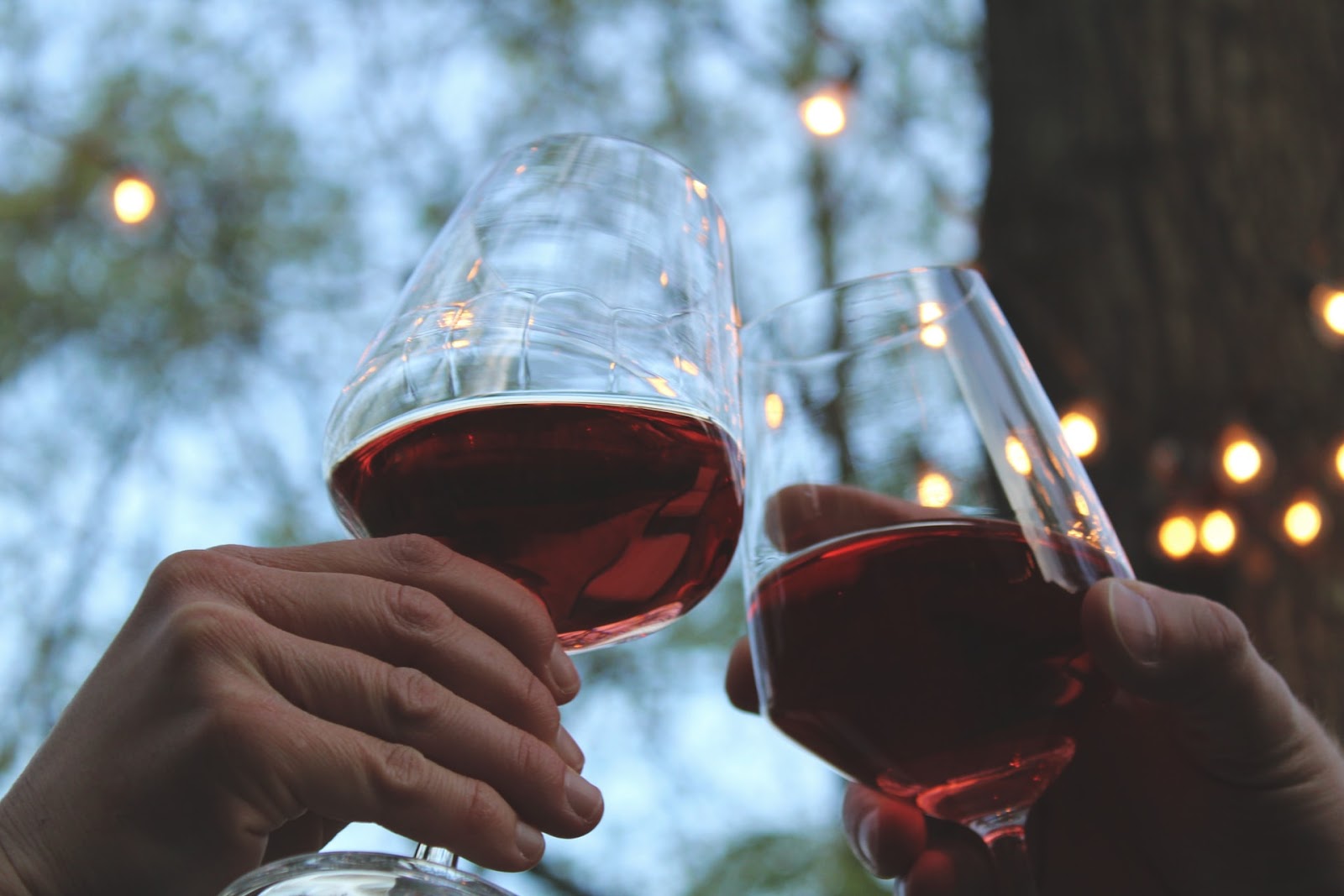 two hands clinking wine glasses together