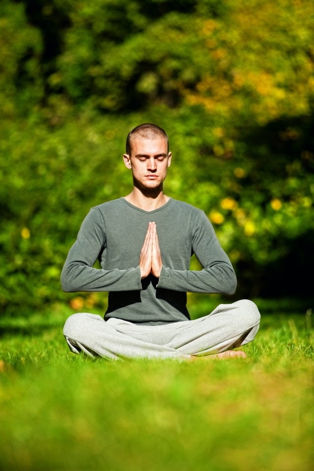 Young man meditating in morning in a field