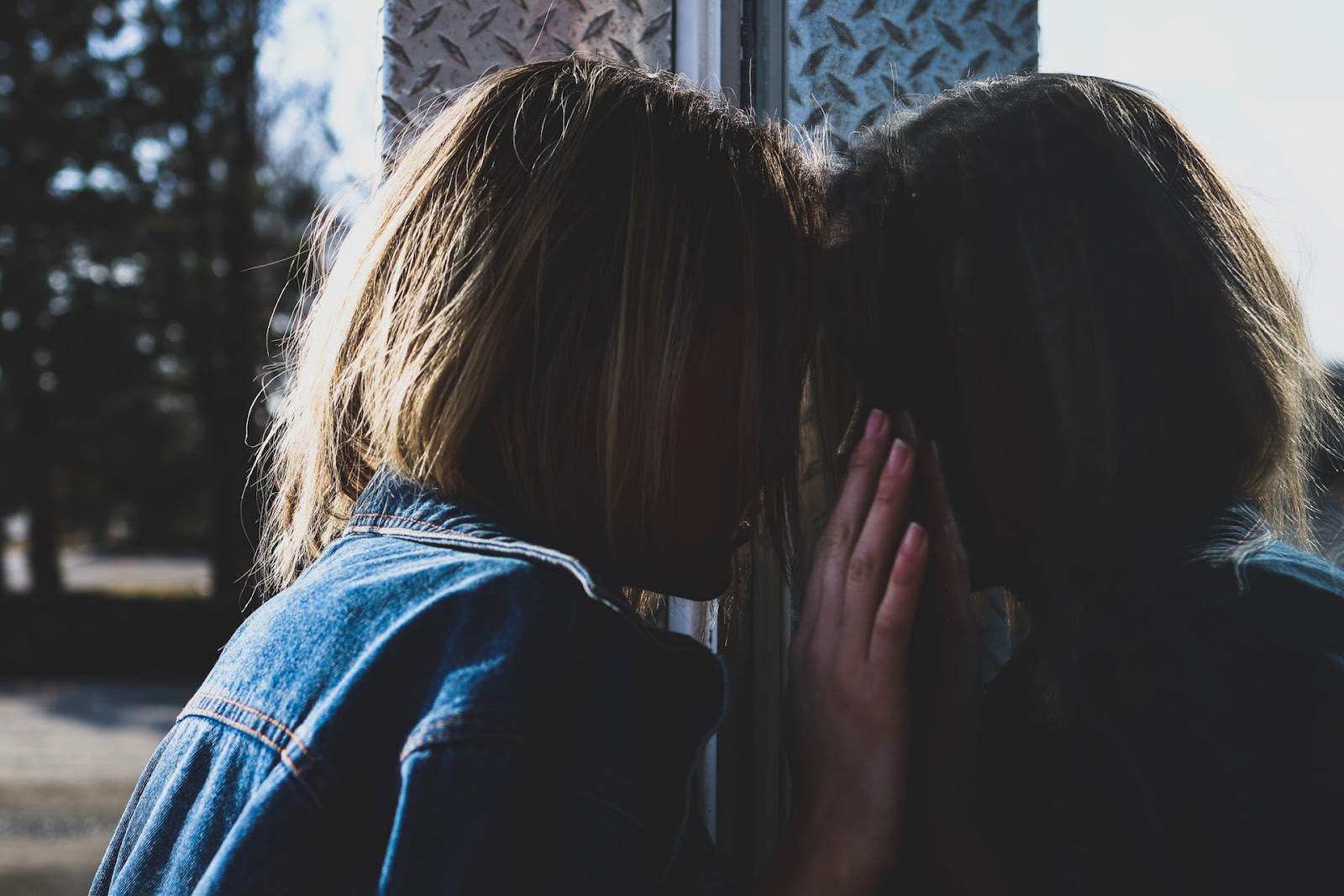 a sad woman pressing her forehead against a window