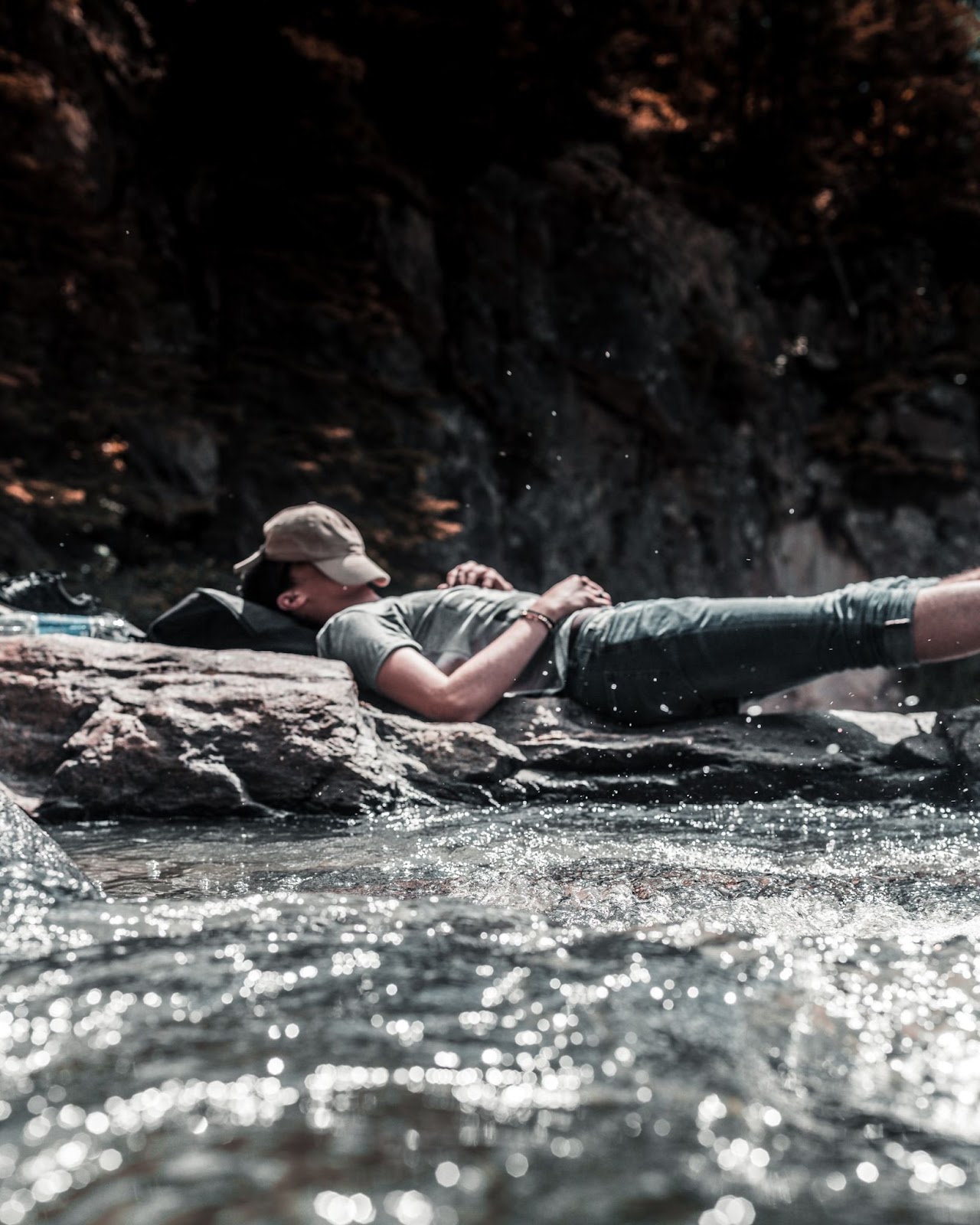 man laying on rocks in the middle of a lake