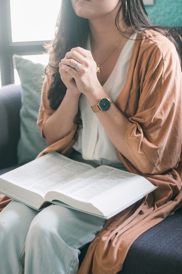 Woman praying with Bible on lap