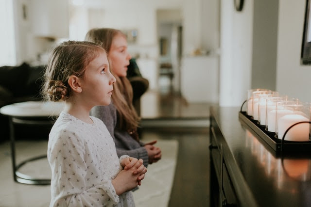Children praying in front of lighted candles