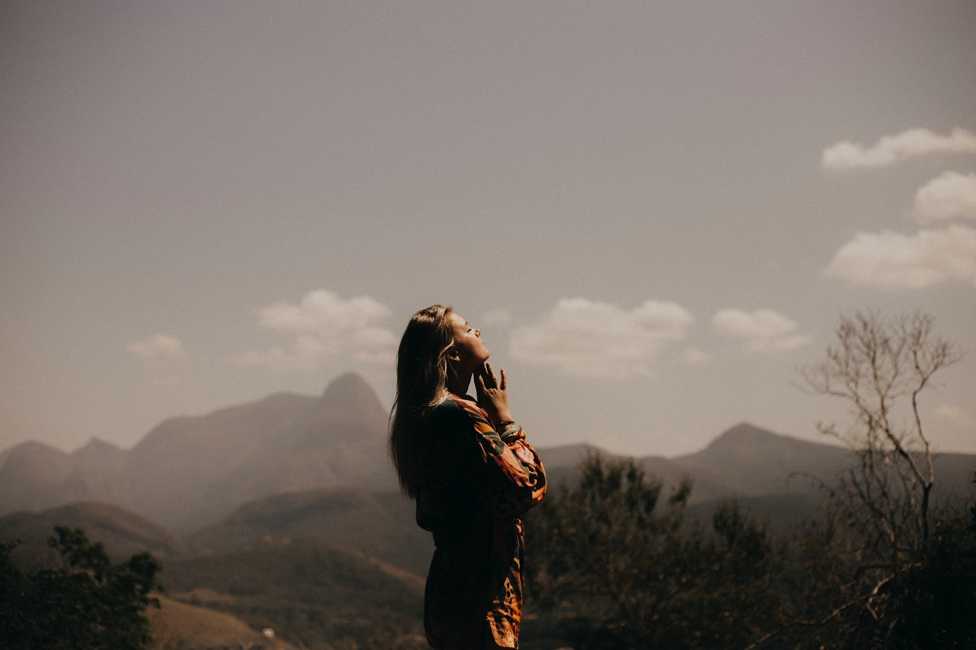 a woman standing in the mountains and praying