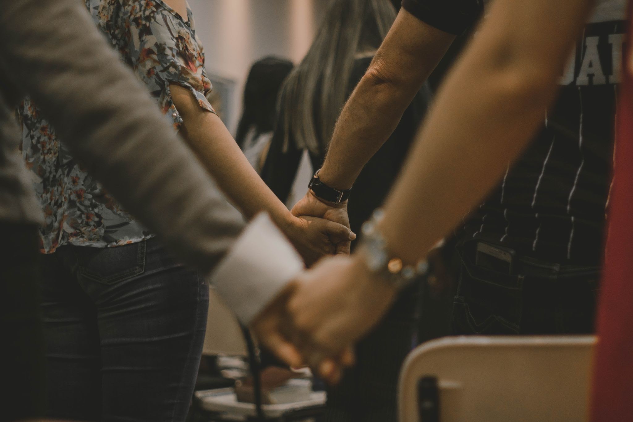 people standing and holding hands in prayer