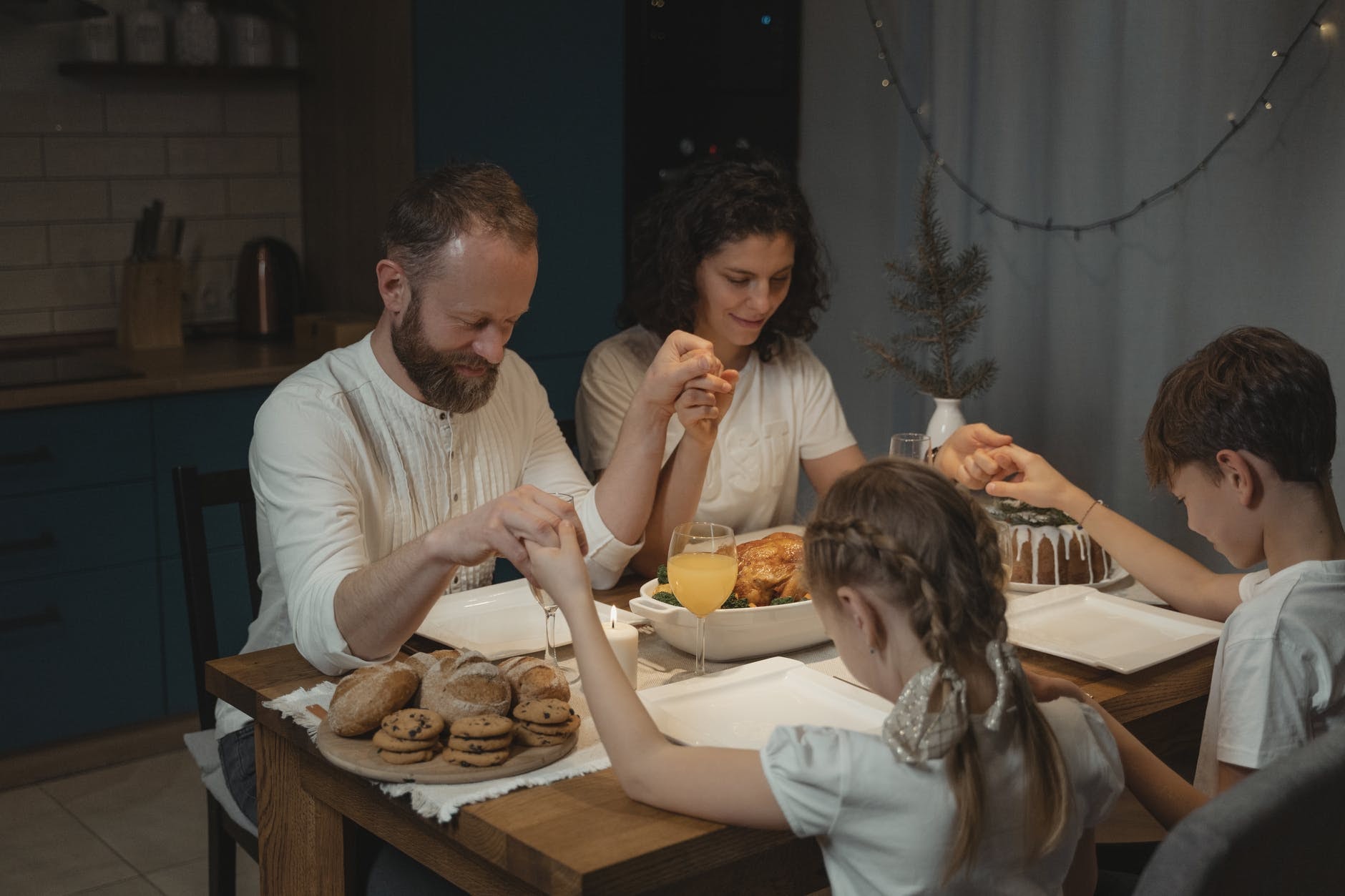 family holding hands in prayer around kitchen table
