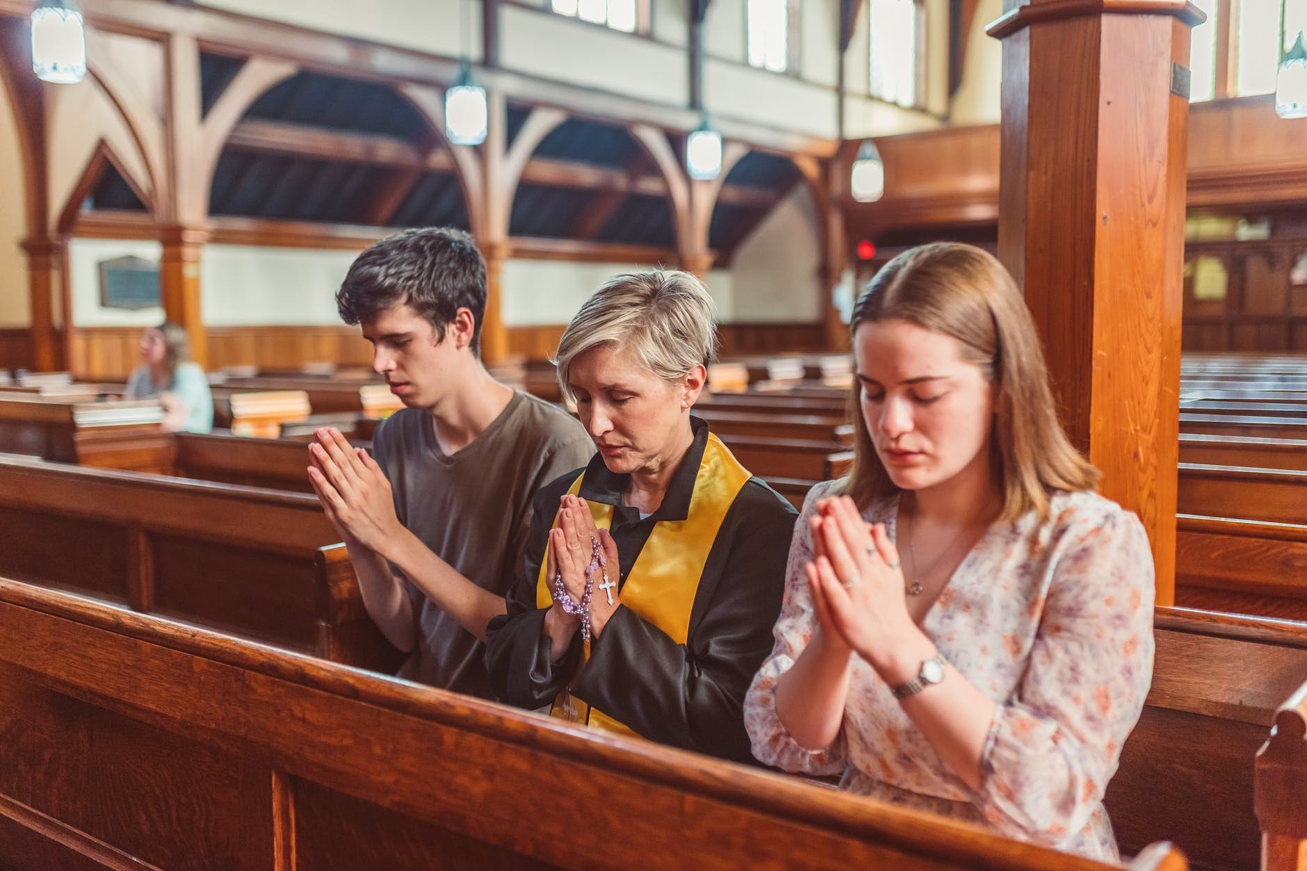 Three people praying together in church.