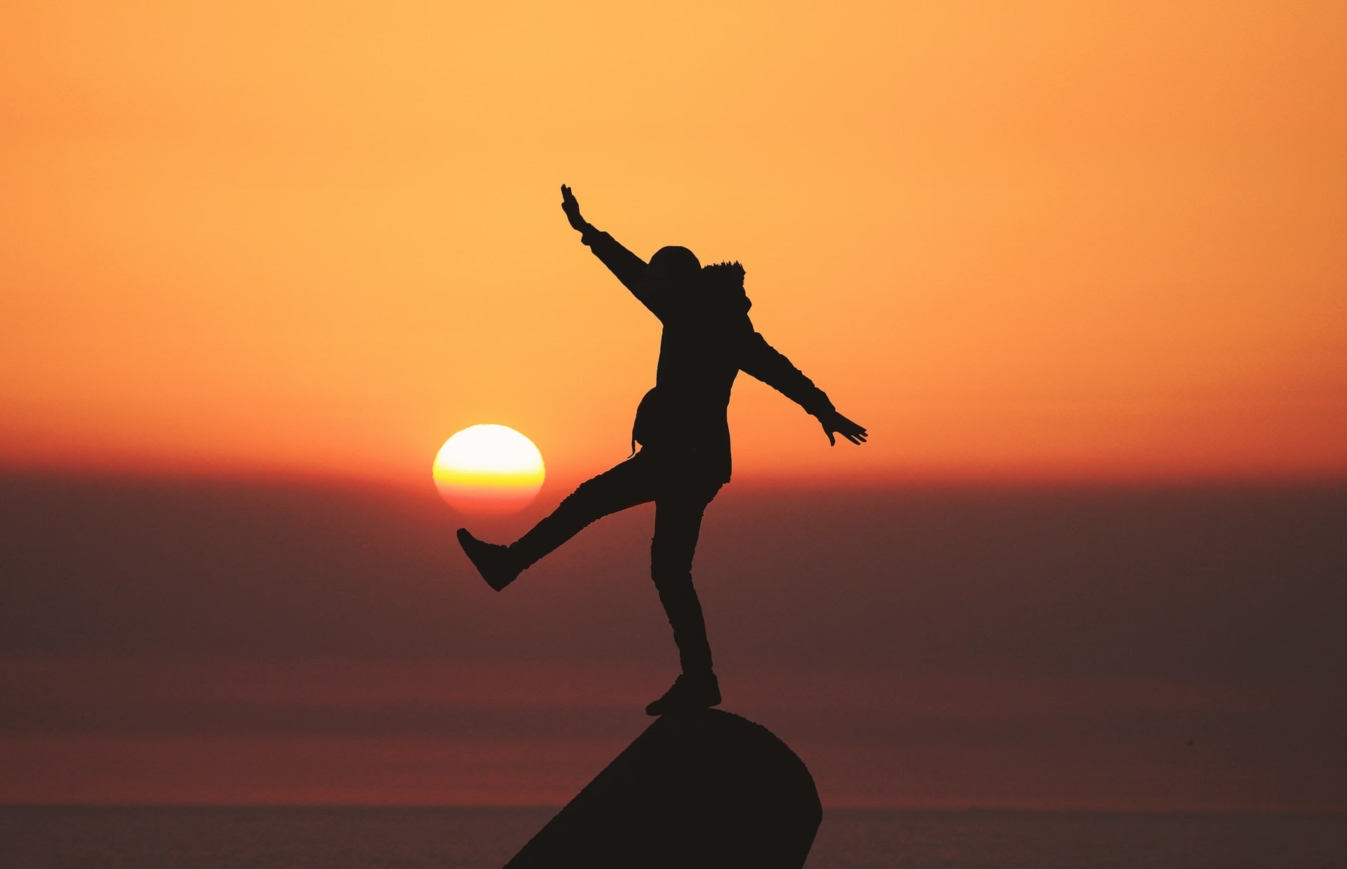 silhouette of a person balancing on something during a sunset