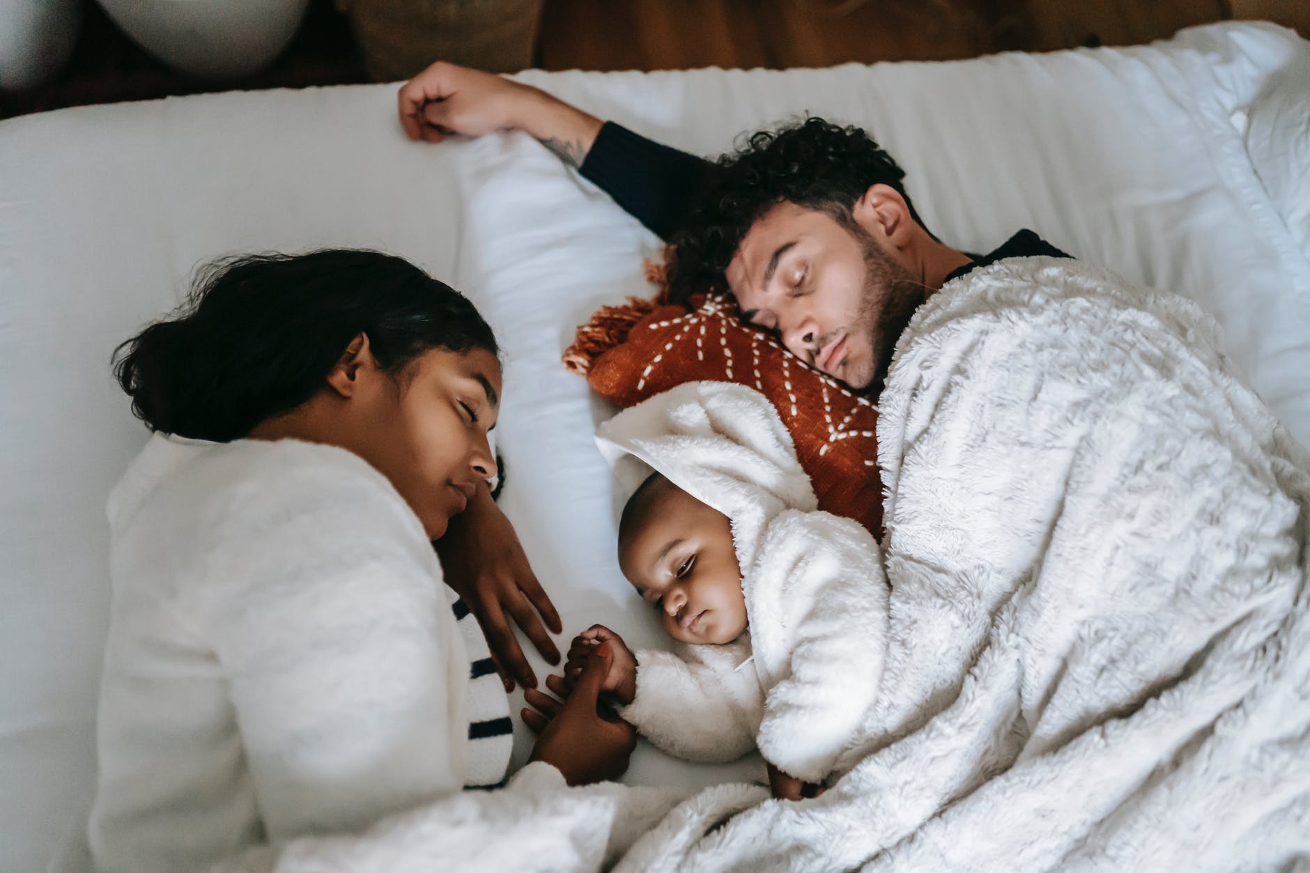 family sleeping together on bed