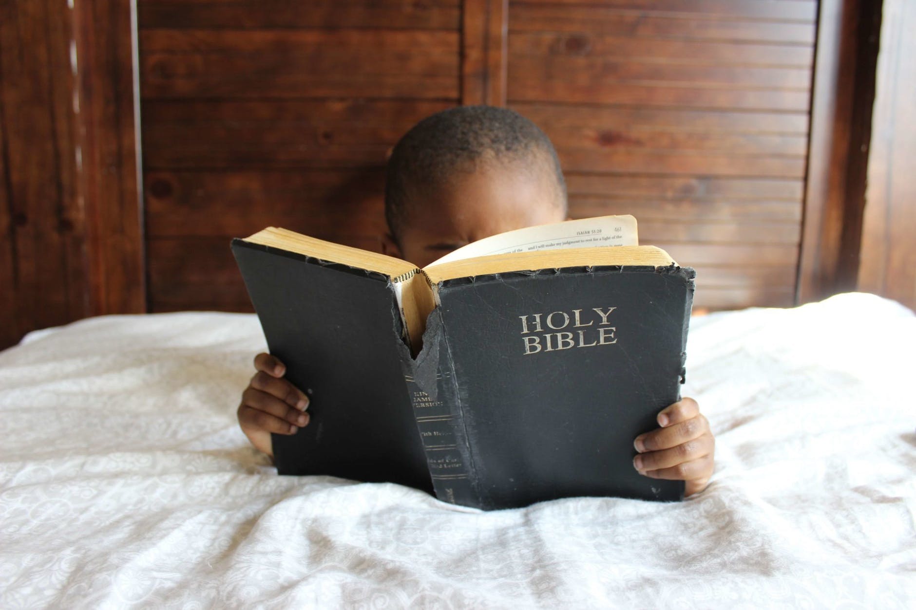 little boy reading the Bible in bed