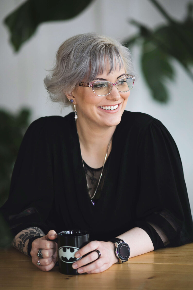 Danielle Wayne, an anxiety therapist in Boise Idaho, looks out the window while sitting at her desk and holding a mug.
