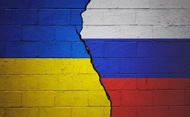 This is the image of Ukraine and Russian flags painted on a brick wall separated by a crack in the middle. The left half contains the Ukrainian flag with blue on top and yellow on the bottom while the right contains the Russian flag with white blue and red colors from top to bottom.