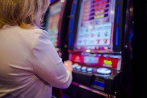 A woman using a slot machine in a casino.