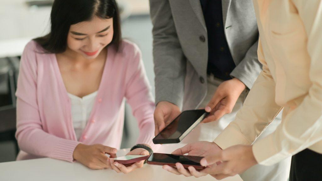 People sharing content on their phones, showing that you need to strive for to get better app retention rate.