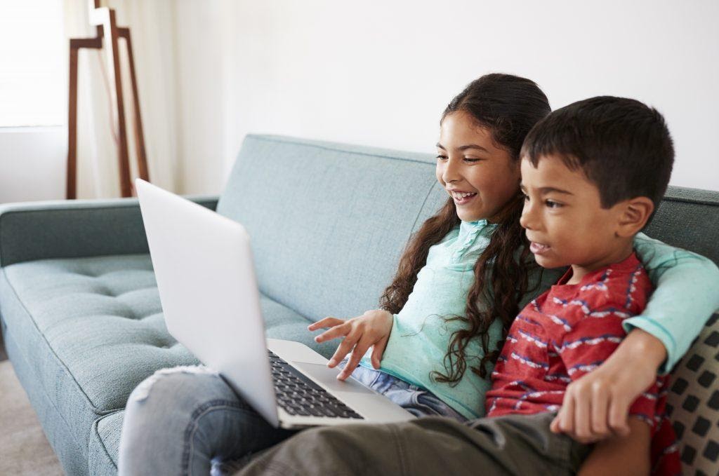 Kids smiling while looking at a laptop, showing a key aspect to keep in mind when considering user attention span in 2021.