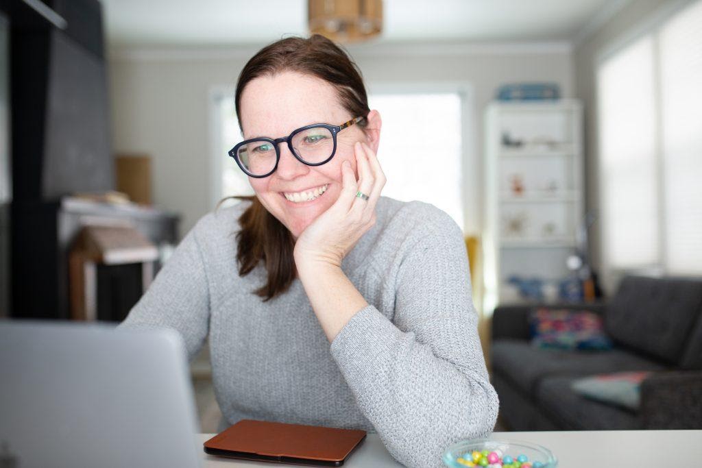 A girl smiling while viewing something on a computer.
