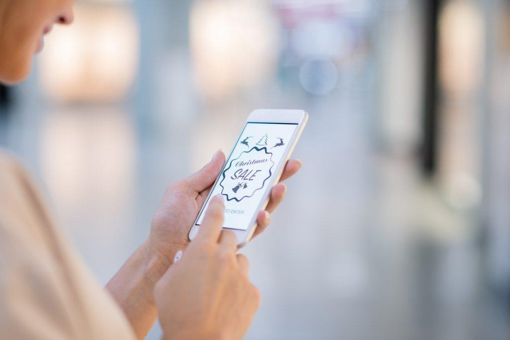 A person viewing a well made Christmas sale add on her phone, showing one of the benefits of visual marketing.