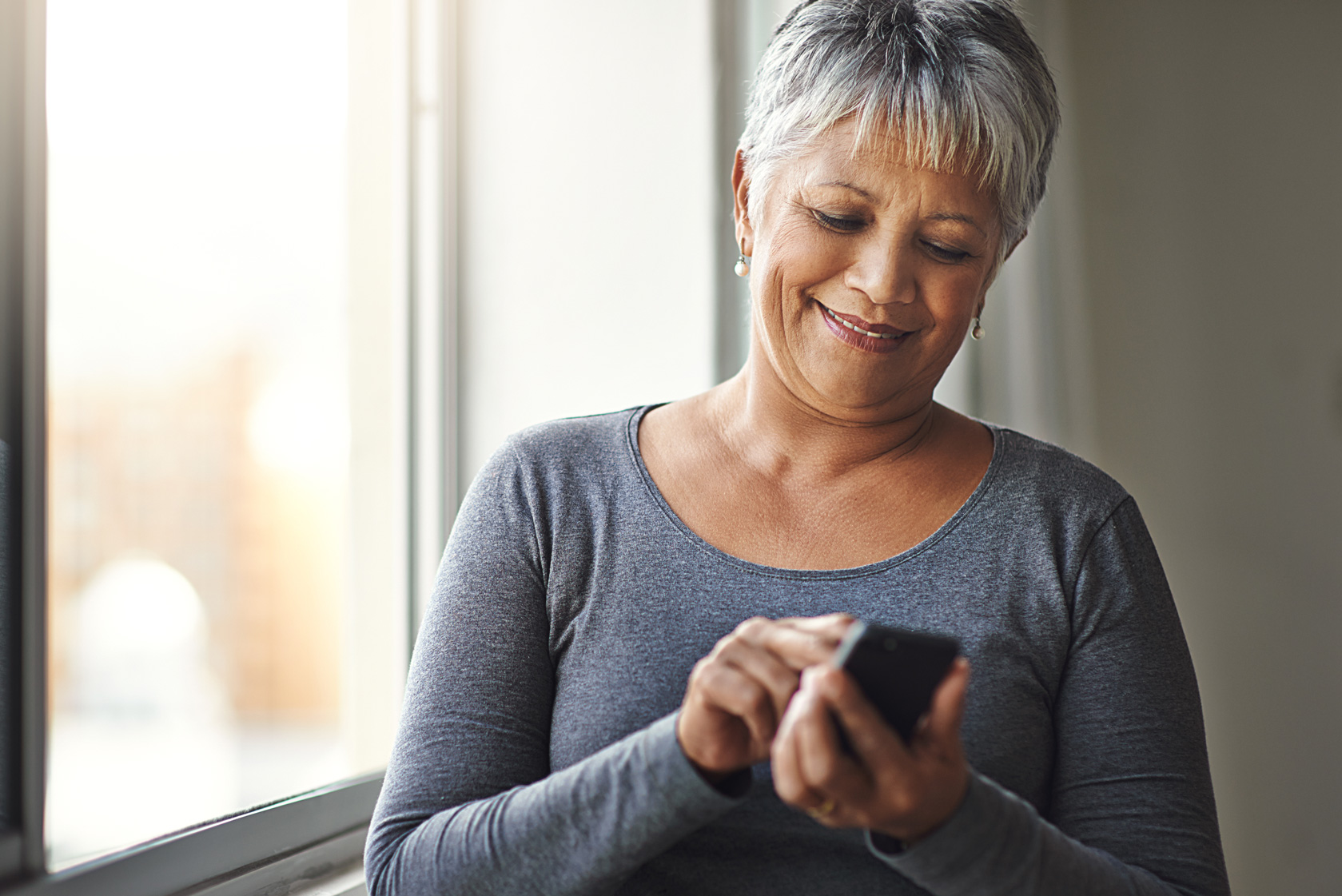 senior hispanic woman looking at a message on their phone from their medical provider.