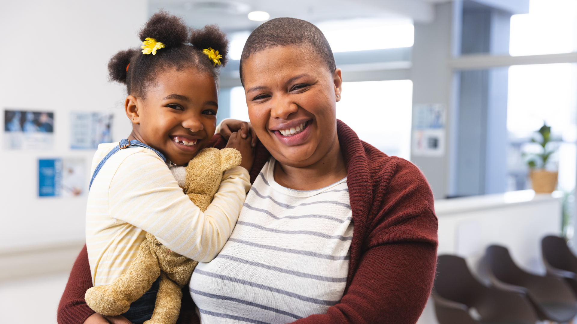 A mother happily holding her daughter inside of a clinic.