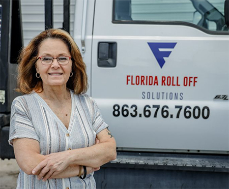 Pam Mosser stands next to her Florida Roll Off Solutions hauling truck