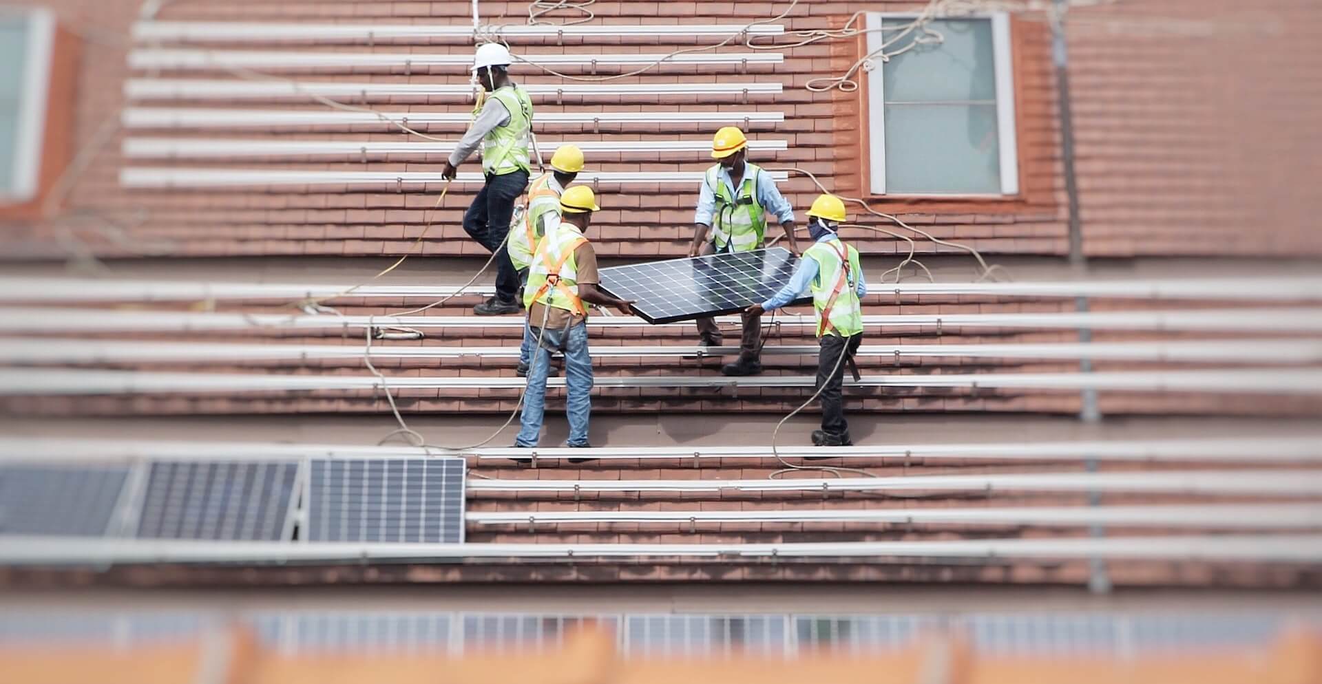 Workers installing solar panels on the roof of a business to reduce costs