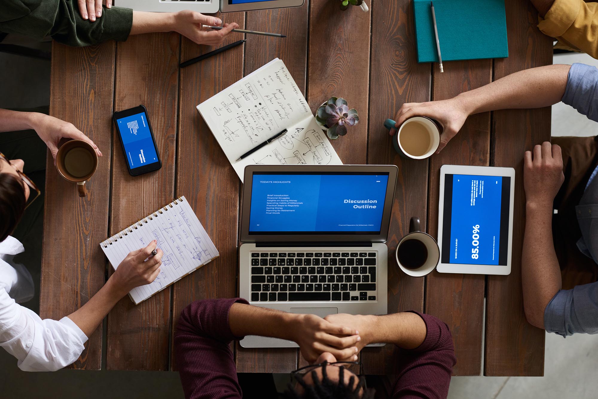 Gruppe von Menschen arbeiten an einem Tisch mit Notizbüchern und Laptops