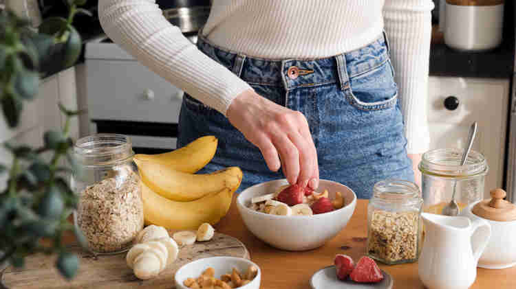 Hands eating oatmeal and other fruits