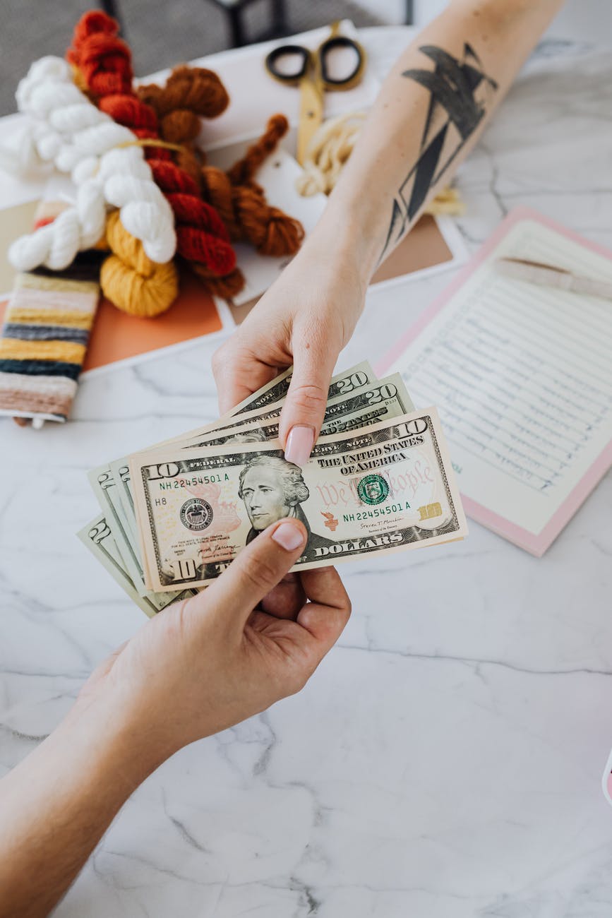 Dua tangan memegang uang kertas dolar