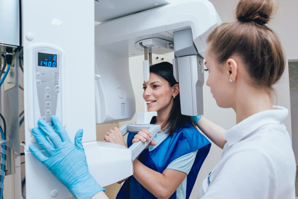 A dentist woman is preparing her patient to Dental Tomography examination.