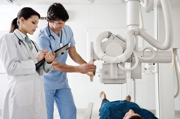 Female doctor and male nurse are preparing a patient for a x-ray examination.