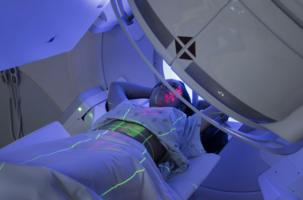 Young woman lying in the RT machine during treatment.