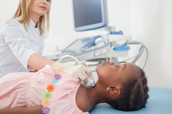 A girl is lying on the bed and having USG thyroid examination.